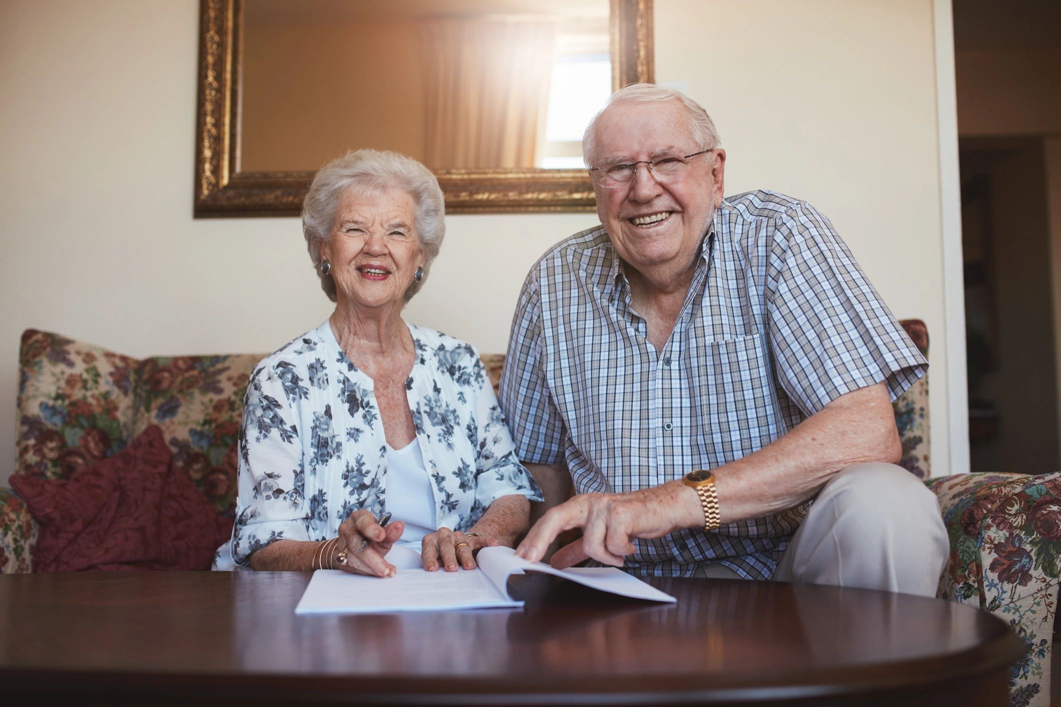 Smiling retired couple reviewing documents at home
